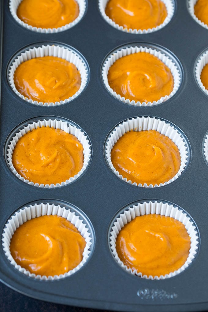 Pumpkin Cupcakes Recipe | Pumpkin Cake #cake #cupcakes #pumpkin #frosting #baking #fall #thanksgiving #ezlod Batter inside paper cups in a muffin tin.