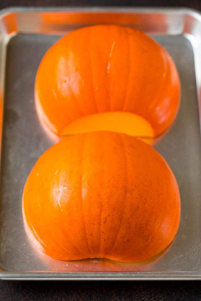 Pumpkin Puree Recipe #pumpkin #baking #fall #thanksgiving #ezlod A pumpkin cut in half on a sheet pan.