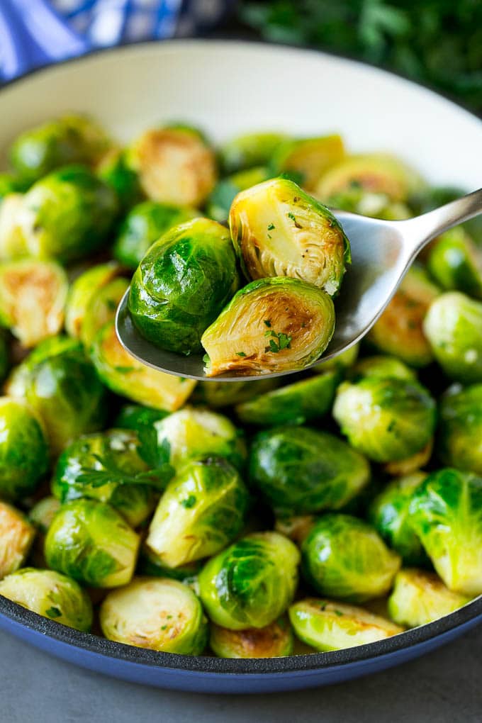 Sauteed Brussels Sprouts Recipe | Brussels Sprouts Side Dish #brusselssprouts #sprouts #veggies #sidedish #garlic #vegetarian #dinner #ezlod A spoon holding up a serving of cooked brussels sprouts.