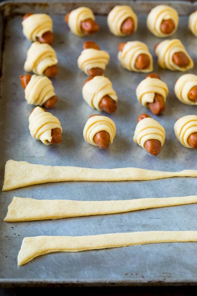 Pigs in a Blanket Recipe #hotdogs #appetizer #snack #comfortfood #ezlod Strips of crescent dough on a sheet pan.