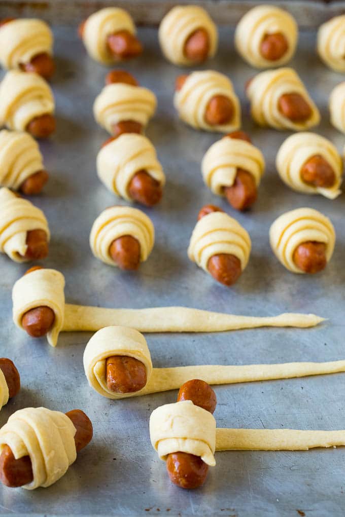 Pigs in a Blanket Recipe #hotdogs #appetizer #snack #comfortfood #ezlod Hot dogs being rolled up in dough.