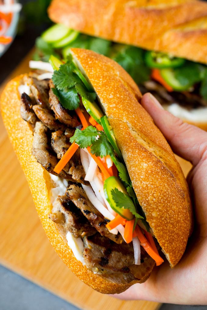 Bahn Mi Sandwich Recipe #sandwich #pork #lunch #dinner #ezlod A hand holding a pork banh mi sandwich.