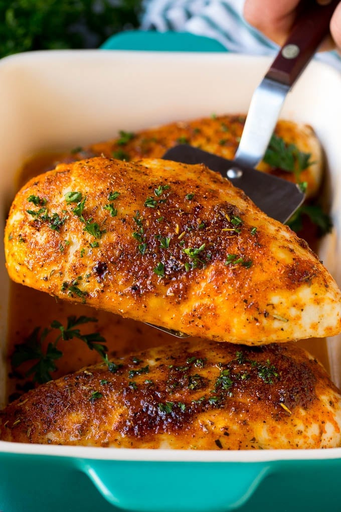 Baked Chicken Breast Recipe #chicken #dinner #ezlod A spatula serving up a portion of roasted chicken breast.