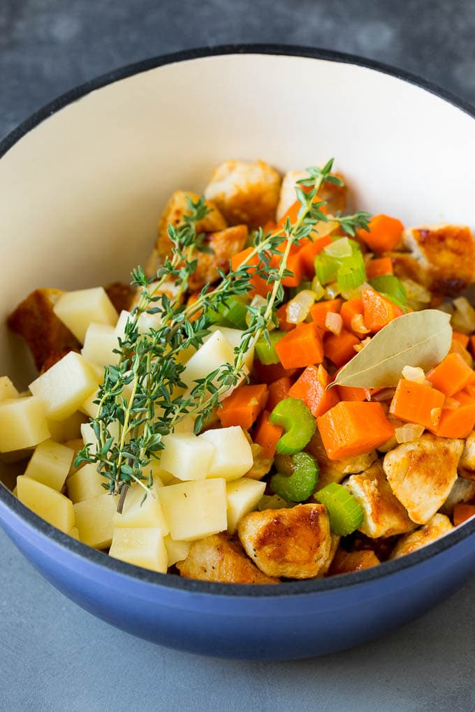 Chicken Pot Pie Soup Recipe | Chicken Soup #soup #chicken #dinner #comfortfood #ezlod Ingredients such as vegetables, potatoes and herbs in a pot.