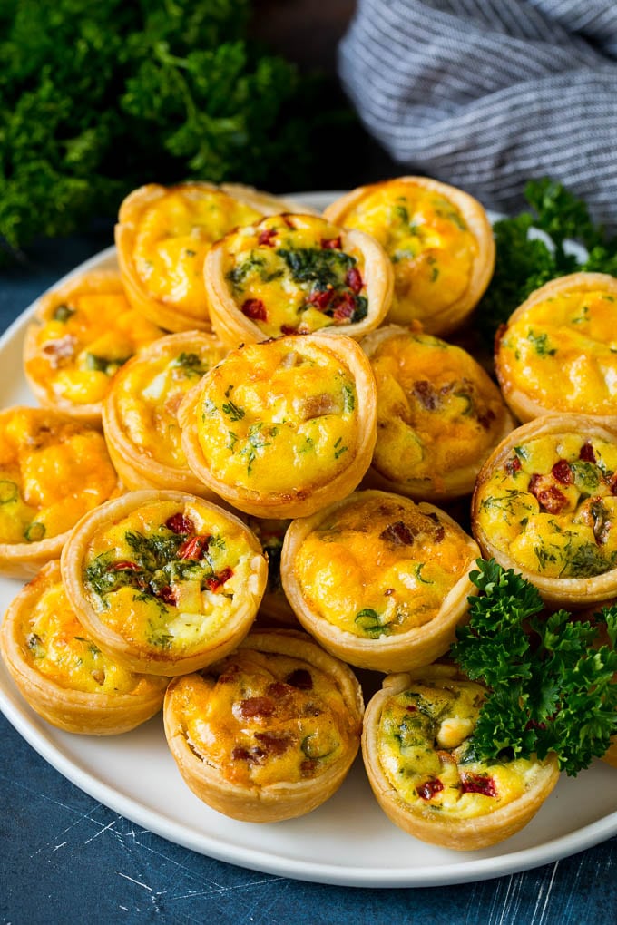 Mini Quiche Recipe #eggs #breakfast #brunch #appetizer #ezlod A plate of mini quiche filled with meats, vegetables and cheeses.