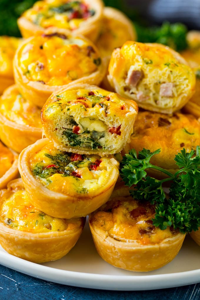 Mini Quiche Recipe #eggs #breakfast #brunch #appetizer #ezlod A serving platter of mini quiche with some cut in half.