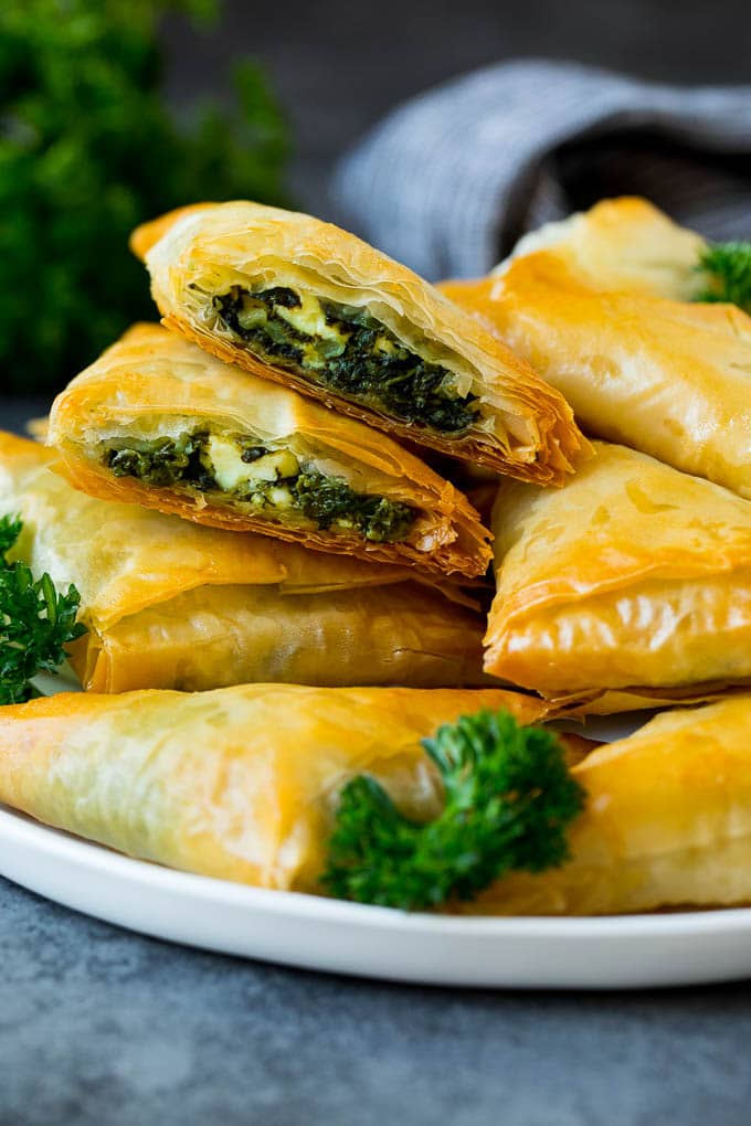 Spanakopita Recipe #appetizer #snack #spinach #cheese #ezlod A plate of spanakopita with two cut in half.
