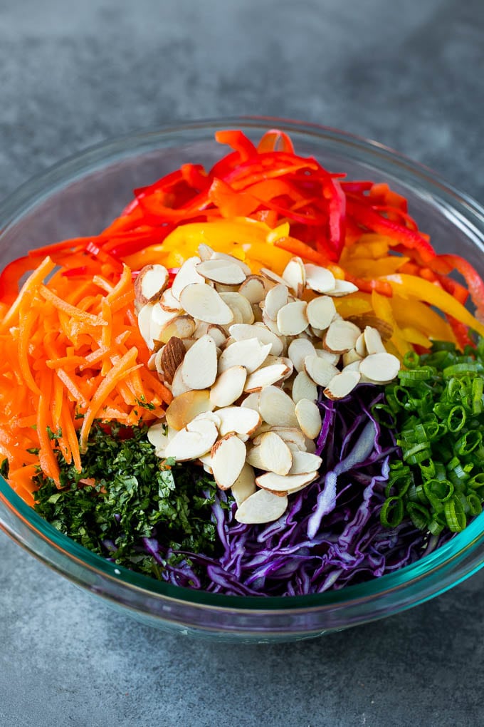 Asian Slaw Recipe #salad #slaw #sidedish #ezlod Shredded cabbage, vegetables and almonds in a bowl.