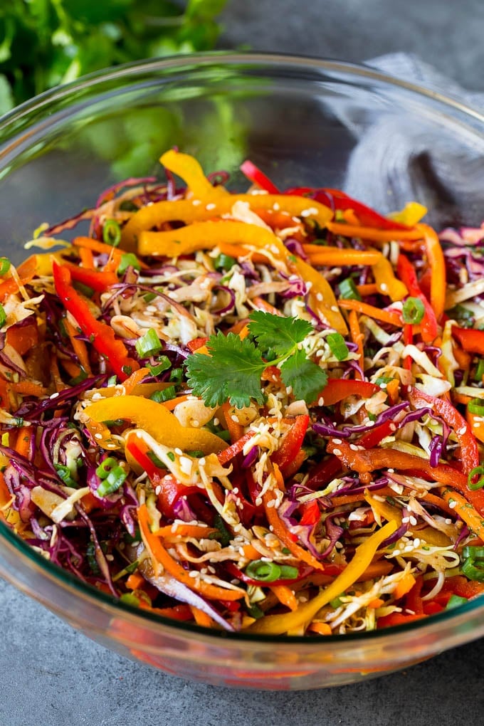 Asian Slaw Recipe #salad #slaw #sidedish #ezlod A bowl of Asian slaw garnished with sesame seeds and herbs.