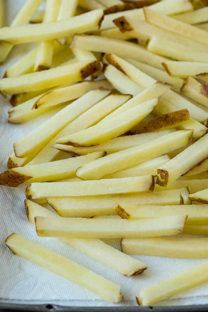Homemade French Fries Recipe #potatoes #fries #dinner #ezlod Potatoes cut into fry shapes on a paper towel lined pan.