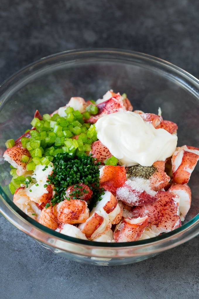 Lobster rolls stuffed with creamy lobster salad in a toasted bun. #lobster #ezlod Lobster, chives, celery and mayonnaise in a bowl.