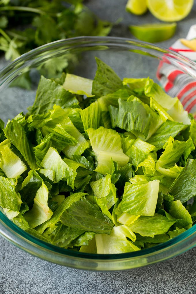 Mexican Salad Recipe #salad #corn #beans #avocado #tomatoes #ezlod Chopped romaine lettuce in a bowl.