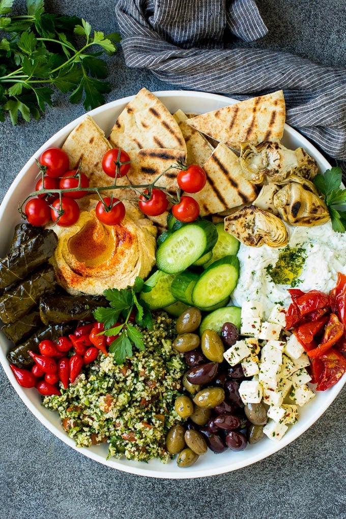 This mezze platter is filled with Mediterranean delicacies including dolmas, hummus, vegetables, pita bread and salads. #appetizer #ezlod A mezze platter filled with dips, pita bread, vegetables, olives and cheese.