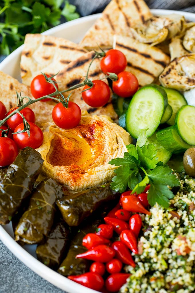 This mezze platter is filled with Mediterranean delicacies including dolmas, hummus, vegetables, pita bread and salads. #appetizer #ezlod A Mediterranean mezze platter with hummus, dolmas and vegetables.