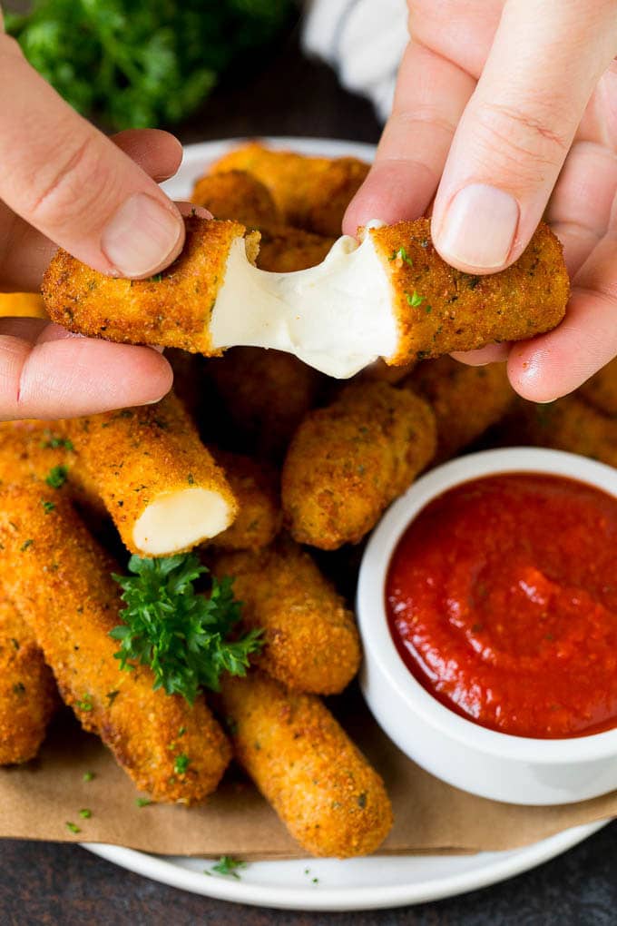 Mozzarella Sticks Recipe #cheese #appetizer #ezlod A hand pulling apart mozzarella sticks.