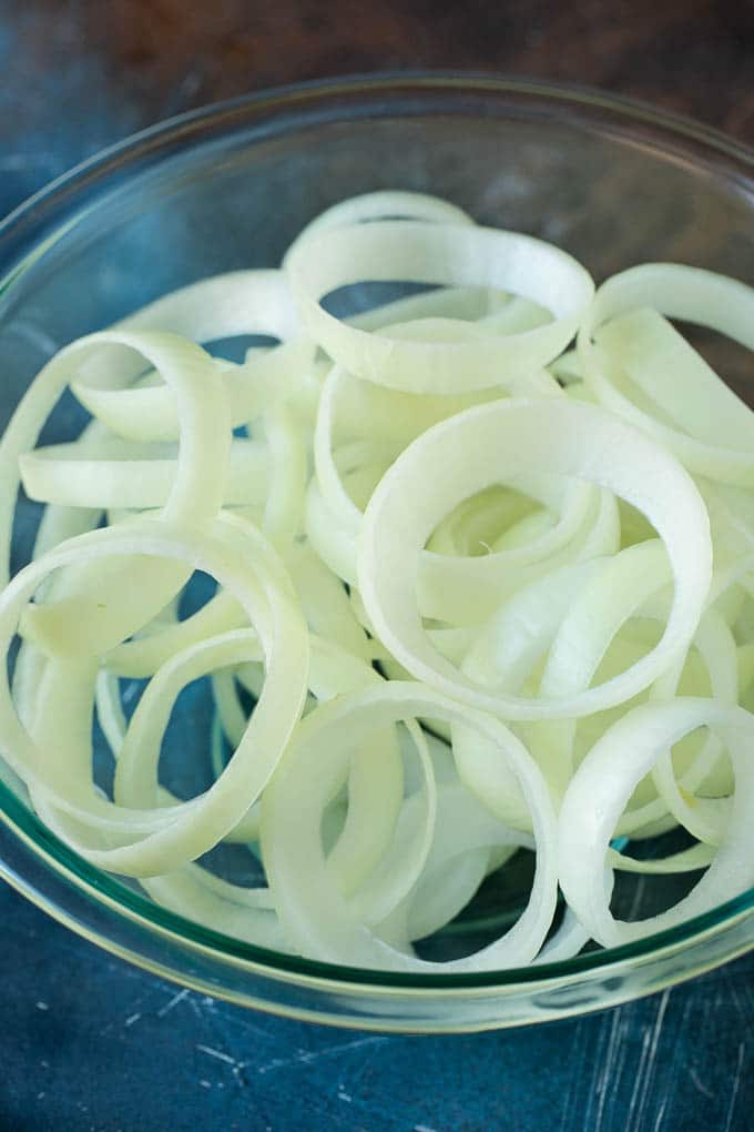 Crispy homemade onion rings that are fried in a flavorful beer batter. #onions #ezlod #appetizer Raw onion slices in a bowl.
