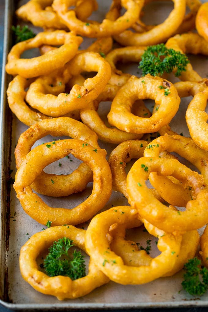 Crispy homemade onion rings that are fried in a flavorful beer batter. #onions #ezlod #appetizer Beer battered onion rings on a sheet pan.