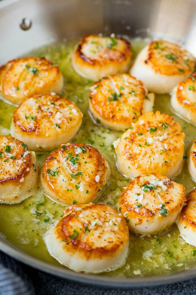 Seared scallops with a garlic and herb butter sauce. An easy and elegant dinner! #seafood #dinner #ezlod A pan of scallops in garlic butter.