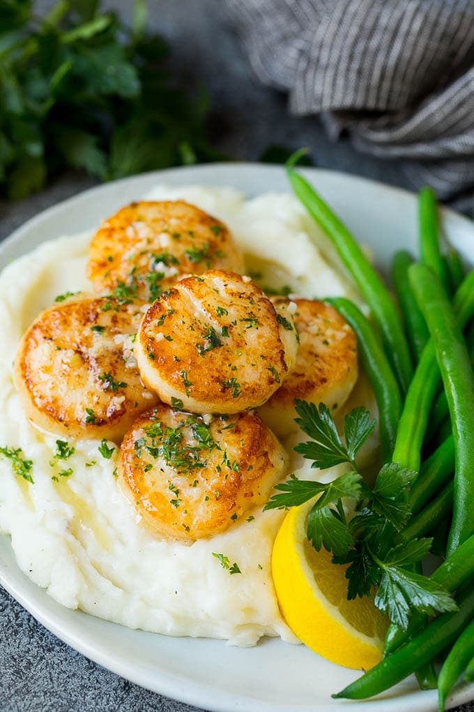 Seared scallops with a garlic and herb butter sauce. An easy and elegant dinner! #seafood #dinner #ezlod Seared scallops served with mashed potatoes and green beans.