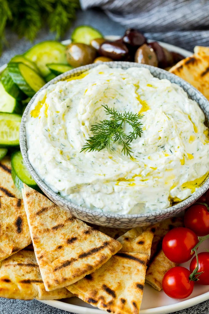 The best homemade tzatziki sauce with cucumber and herbs mixed into Greek yogurt. #appetizer #ezlod A bowl of tzatziki served with pita bread and vegetables.