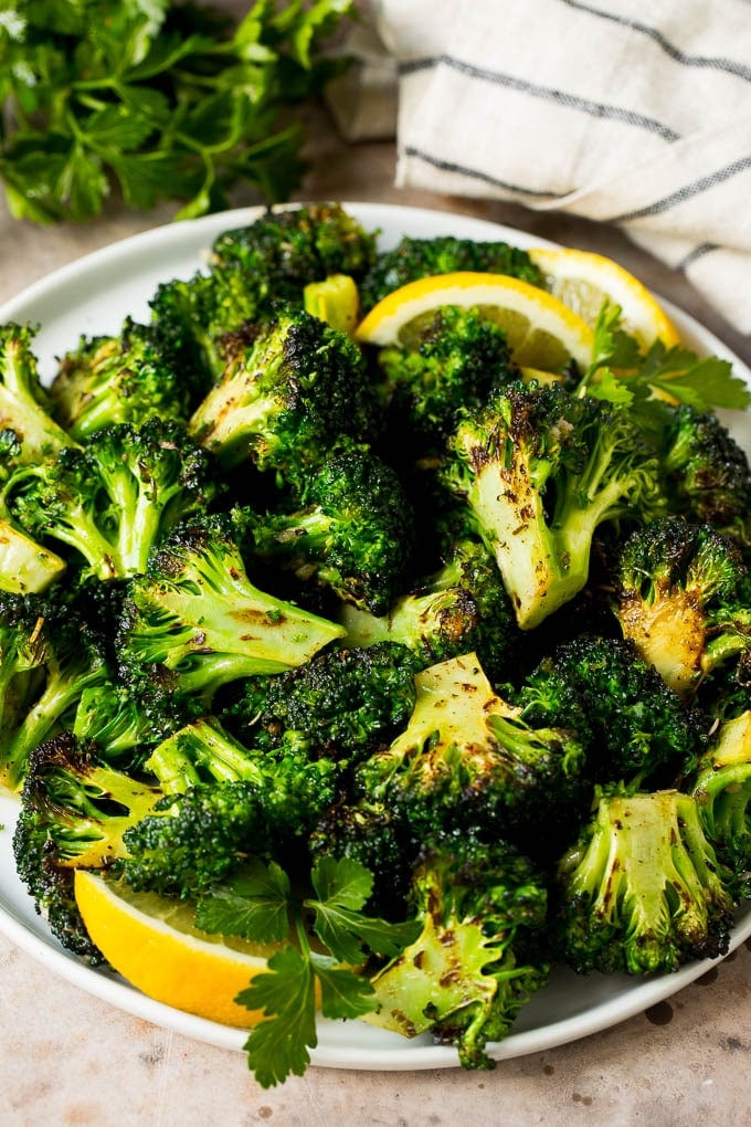 Grilled broccoli is packed with flavor and is a colorful and healthy side dish! #broccoli #ezlod Grilled broccoli topped with parsley and garnished with lemon wedges.