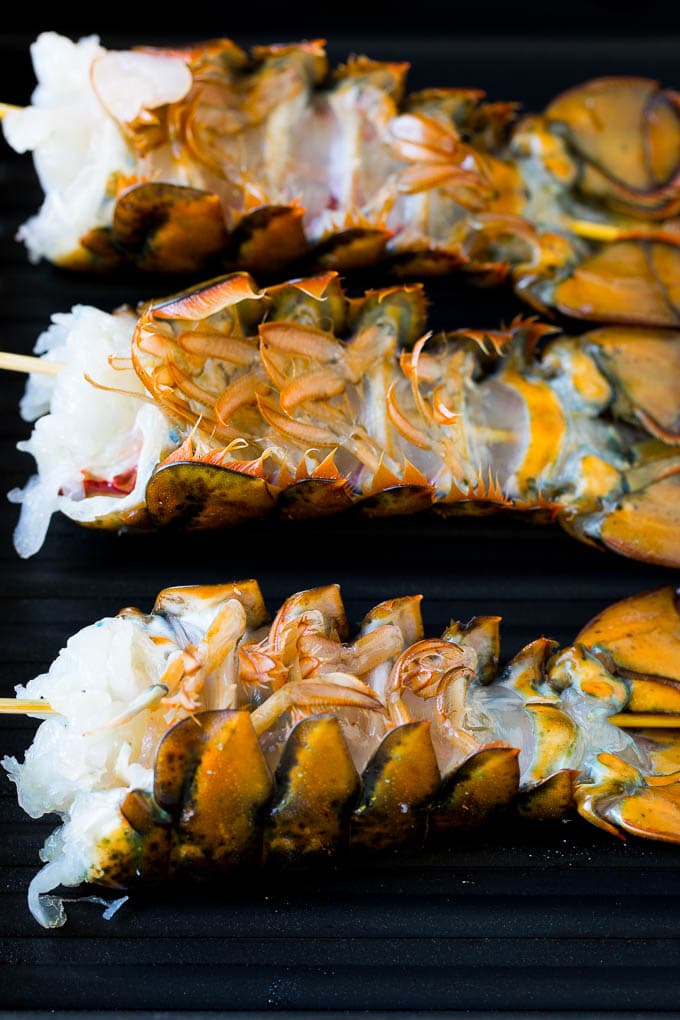 Grilled lobster tail drizzled with garlic butter is an easy and elegant dinner option. #lobster #ezlod Lobster tails upside down on a grill pan.