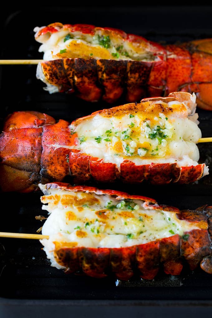 Grilled lobster tail drizzled with garlic butter is an easy and elegant dinner option. #lobster #ezlod Cooked lobster tails on a grill pan, brushed with butter.