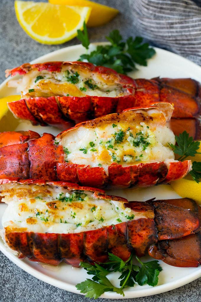Grilled lobster tail drizzled with garlic butter is an easy and elegant dinner option. #lobster #ezlod Grilled lobster tail topped with garlic butter and garnished with lemon and parsley.