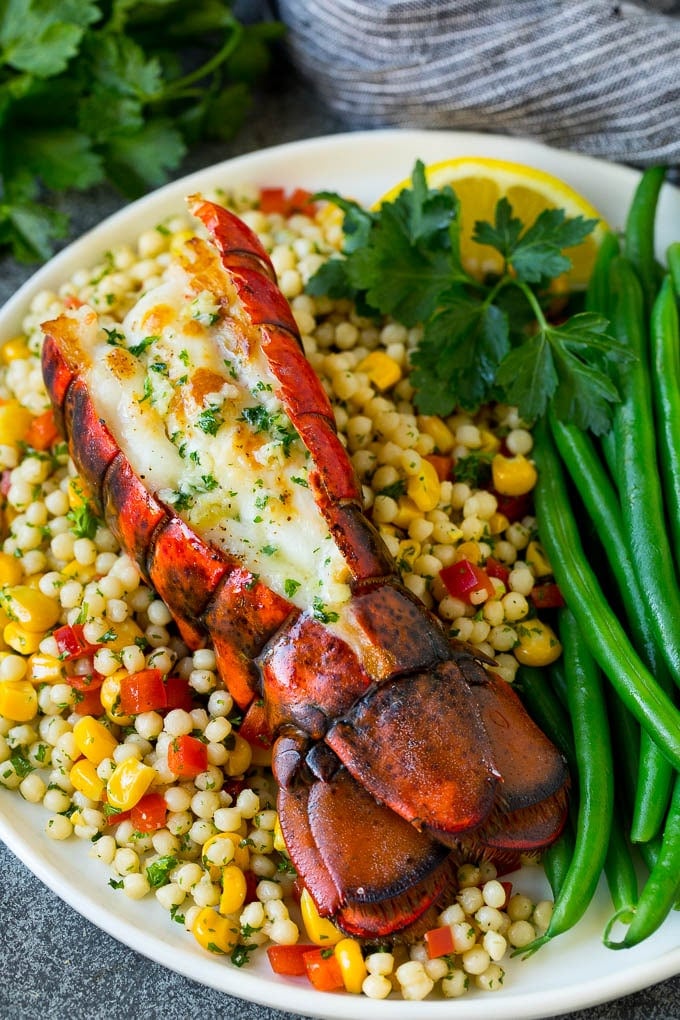 Grilled lobster tail drizzled with garlic butter is an easy and elegant dinner option. #lobster #ezlod Grilled lobster tail served with couscous and green beans.