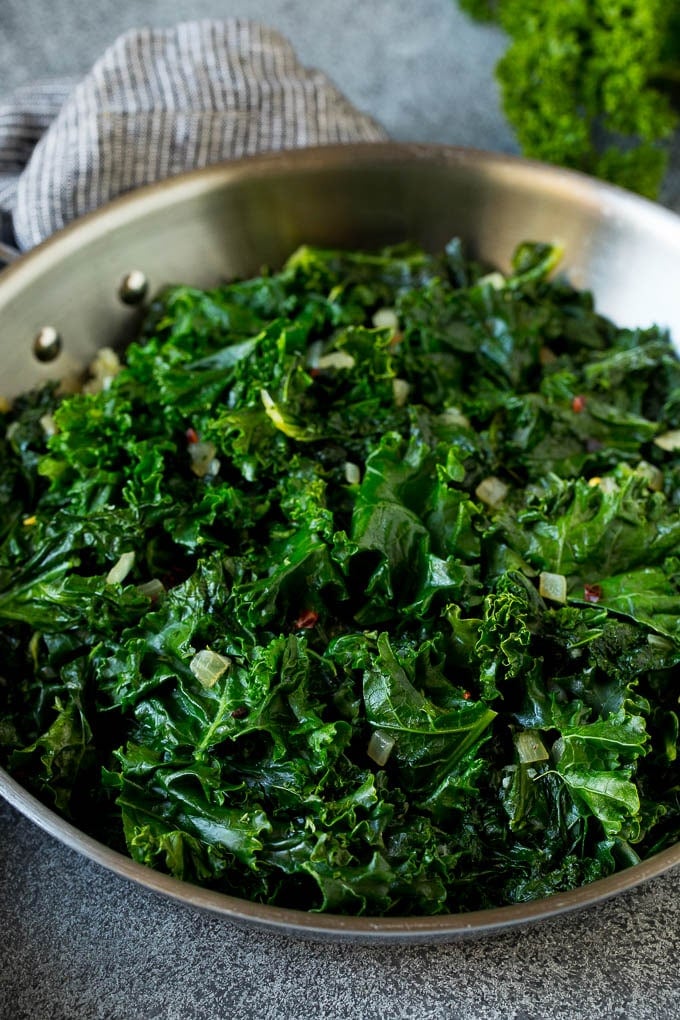 Sauteed kale flavored with olive oil and garlic, a quick and easy side dish! #kale #ezlod Cooked kale with olive oil, onions and garlic.
