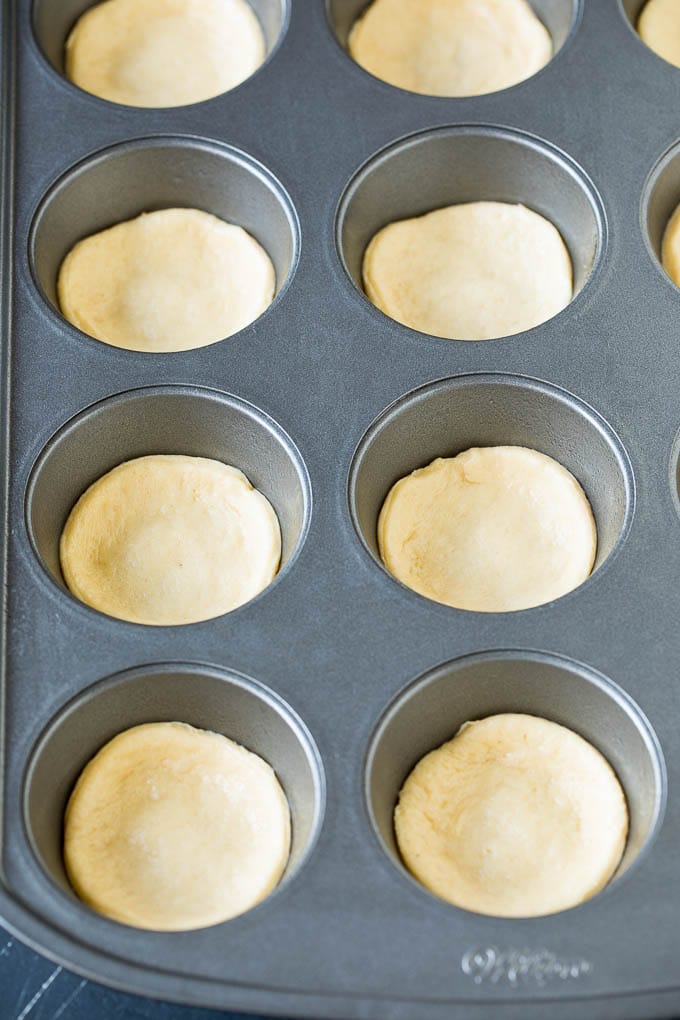 Mini pizzas topped with pepperoni are a fun and easy appetizer option. #pizza #ezlod #appetizer Dough circles pressed into muffin cups.