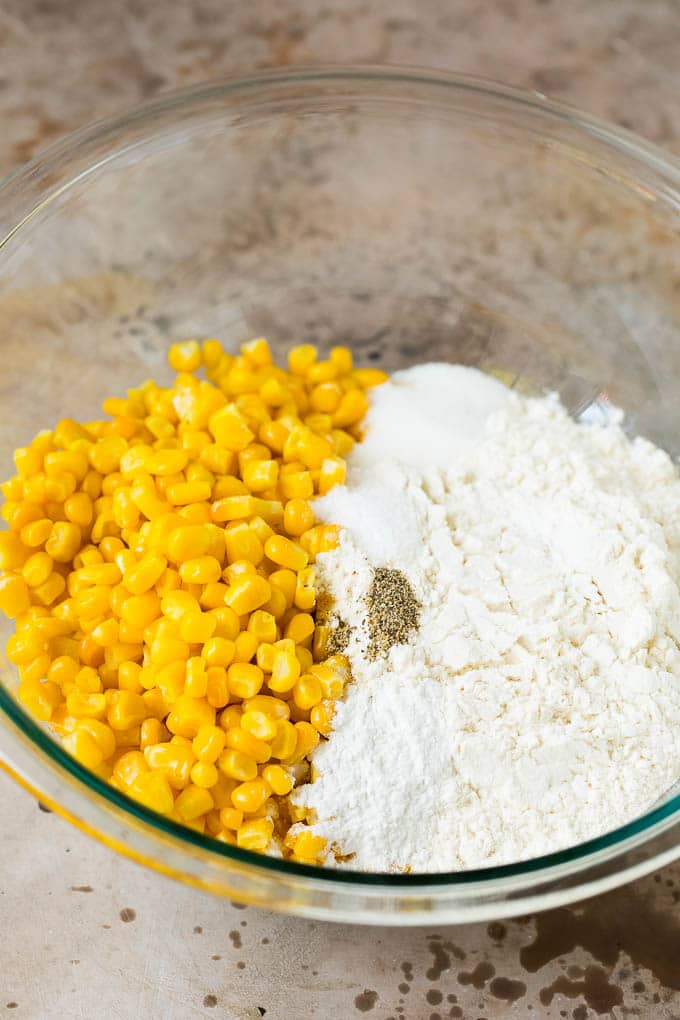 These crispy corn fritters are easy to make and are the perfect appetizer or lighter main course. #corn #ezlod Flour, corn and seasonings in a mixing bowl.
