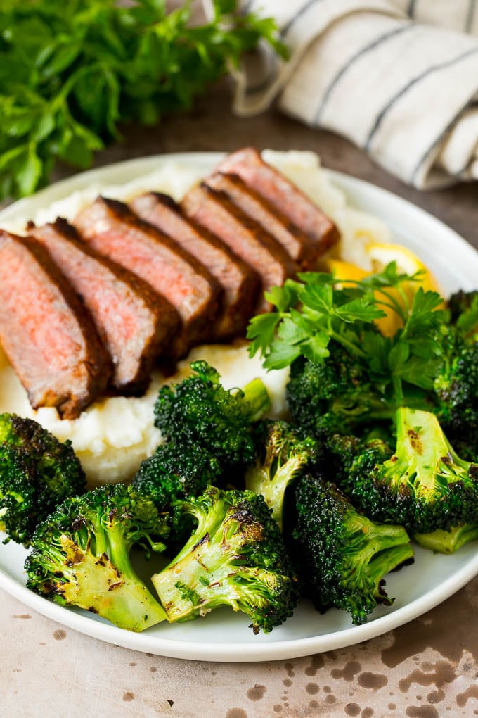 Grilled broccoli is packed with flavor and is a colorful and healthy side dish! #broccoli #ezlod Grilled broccoli on a plate with steak and mashed potatoes.
