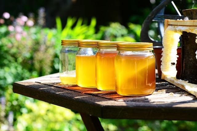 Extracting Honey From Comb into Glass Jars on a Table