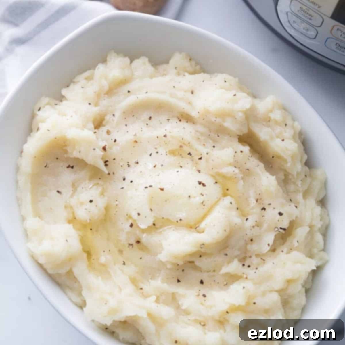 White serving bowl full of mashed potatoes topped with fresh black pepper and melted vegan butter making them dairy free.