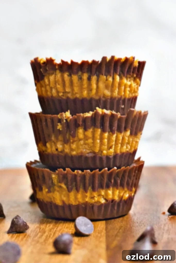 A stack of three homemade chocolate pumpkin cups on a wooden table with chocolate chips tossed around – A perfect clean eating dessert for the 21 Day Fix.