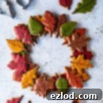 Golden Maple Leaf Vegan Cookie Wreath 9 Autumn leaf maple cookie wreath on a white background with coloured leaf cookies, cookie cutters and bottles of maple syrup.