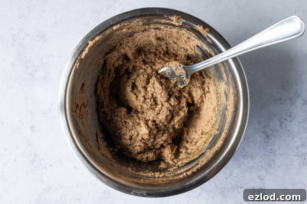 Step-by-step image showing the process of making the maple pecan filling in a bowl, with softened vegan butter, maple syrup, brown sugar, and cinnamon being whisked together.