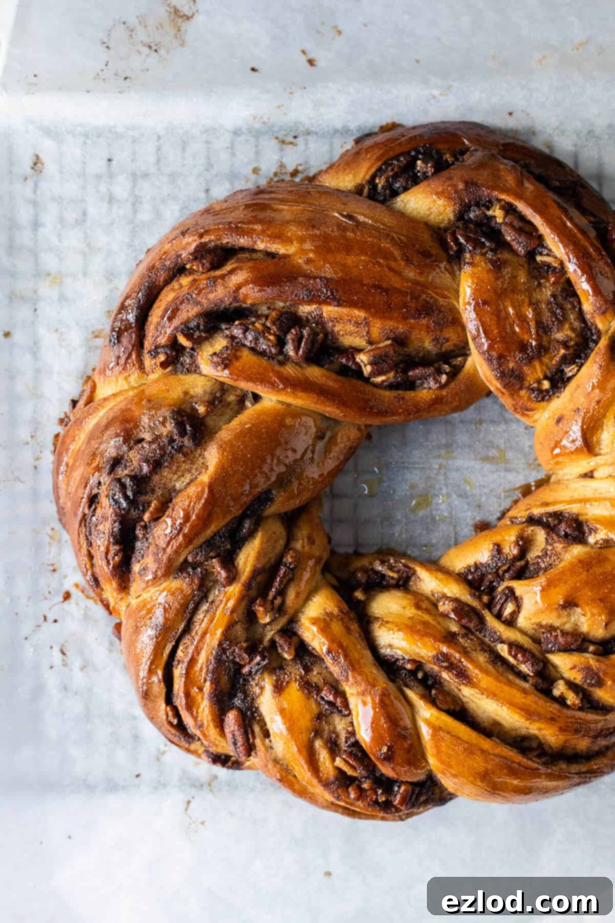 A detailed close-up of an unglazed vegan maple pecan couronne, showcasing its intricate twisted shape and golden-brown crust, ready for its final sweet topping.