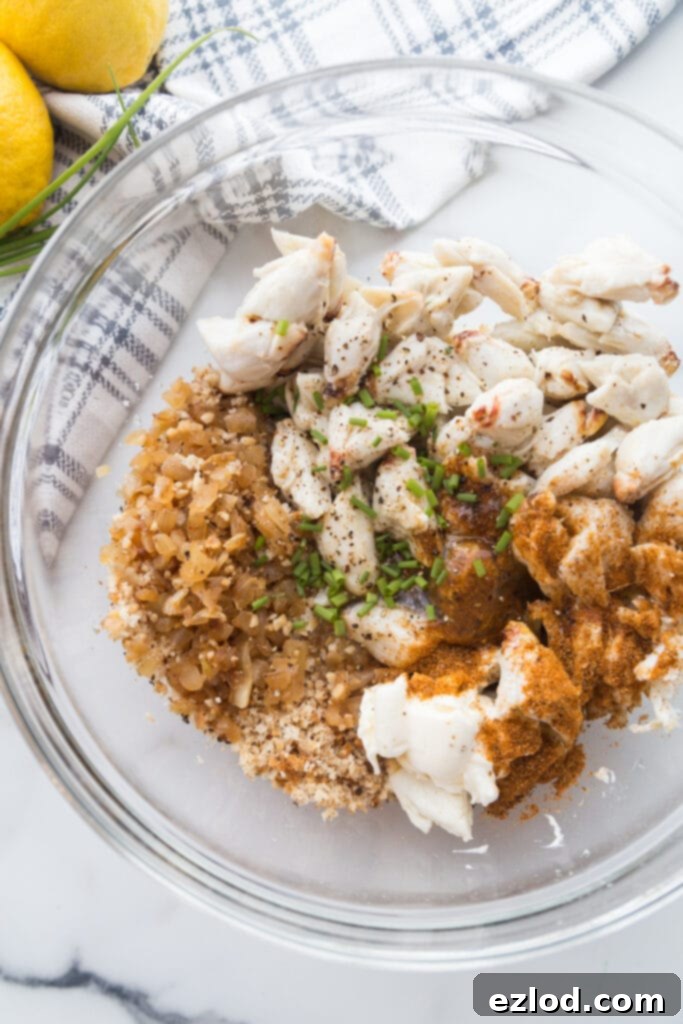 Jumbo lump crab meat in a bowl with sauteed onions, garlic, and chives, breadcrumbs and seasoning