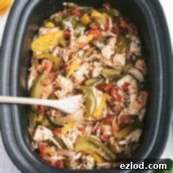 Effortless Slow Cooker Chicken Fajitas 6 Delicious shredded Crockpot Chicken Fajitas with bell peppers and onions in a black slow cooker, ready to serve.