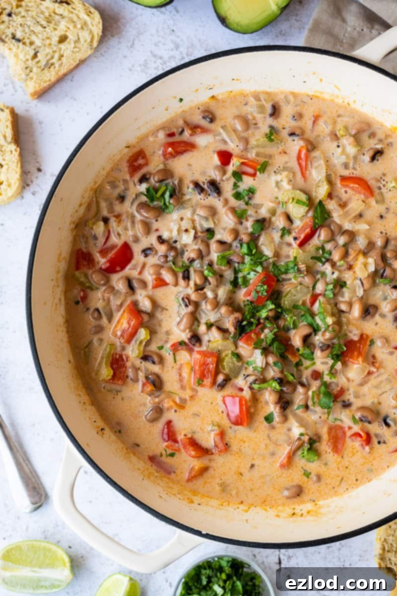 Close up of a white cast iron panful of easy black-eyed bean soup topped with chopped coriander. This quick and easy black eye bean, vegetable and coconut soup is a fast, delicious and healthy vegan option for lunch or dinner.