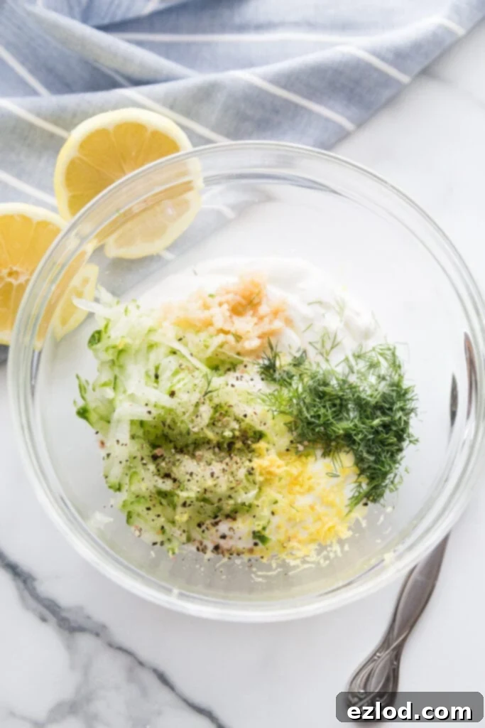 Overhead photo of glass bowl filled with ingredients to make homemade tzatziki dressing to top Easy Falafel Bites
