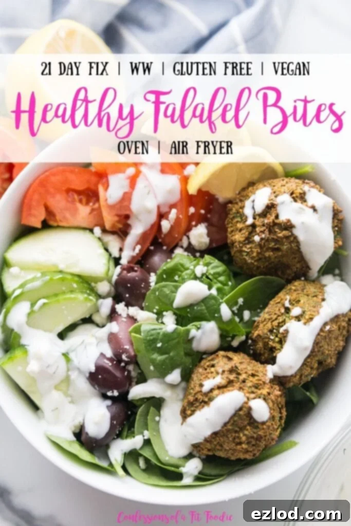 Overhead photo of large white bowl filled with Falafel bites and veggies including spinach, cucumbers, tomatoes, and olives, topped with tzatziki dressing with lemon wedges on the side; with the text overlay, 21 Day Fix | WW | Gluten Free | Vegan | Healthy Falafel Bites | Oven | Air Fryer