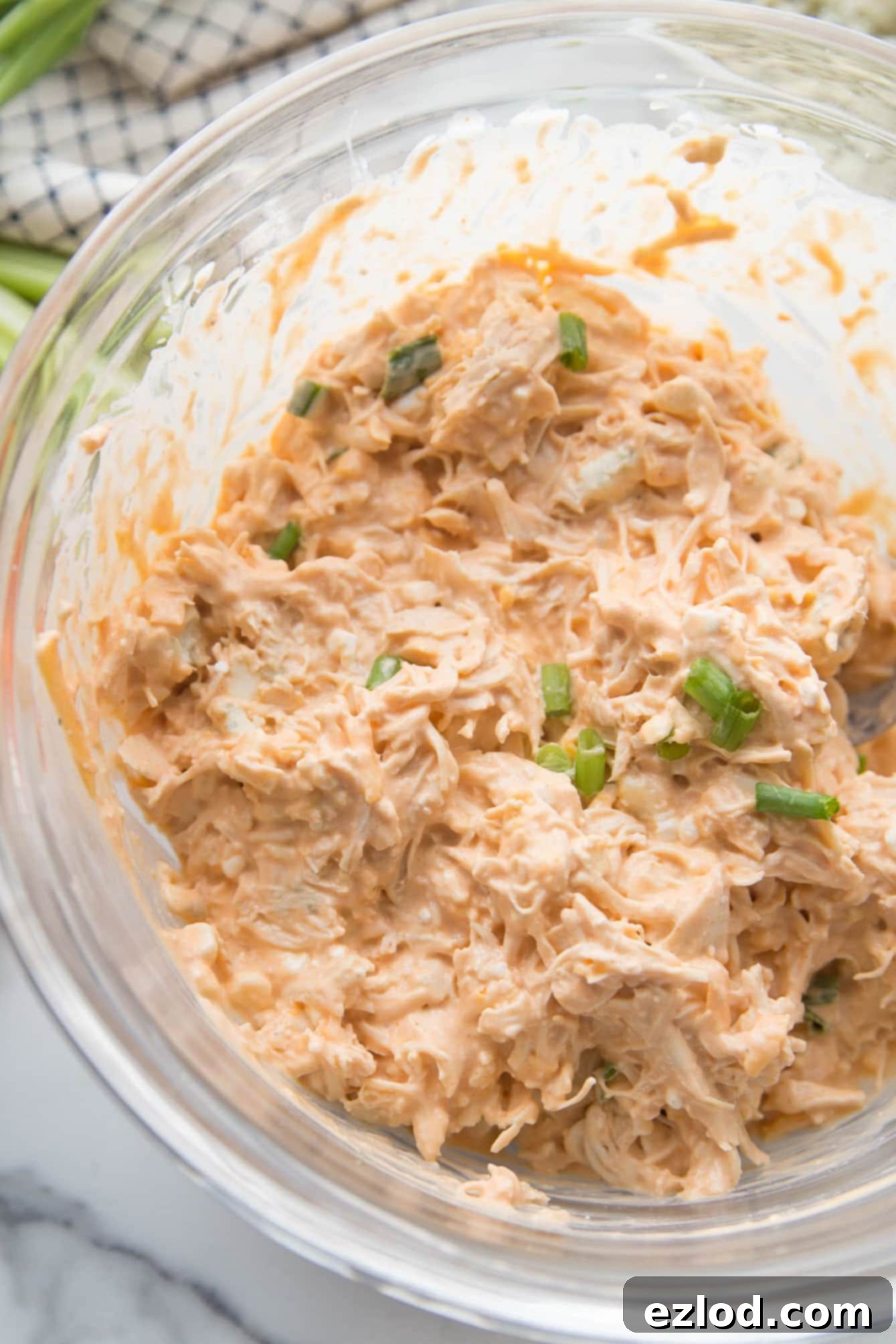 Fiery Buffalo Chicken Stuffed Peppers 7 Overhead view of healthy buffalo chicken dip, perfectly mixed with shredded chicken and topped with thinly sliced green onions for garnish.