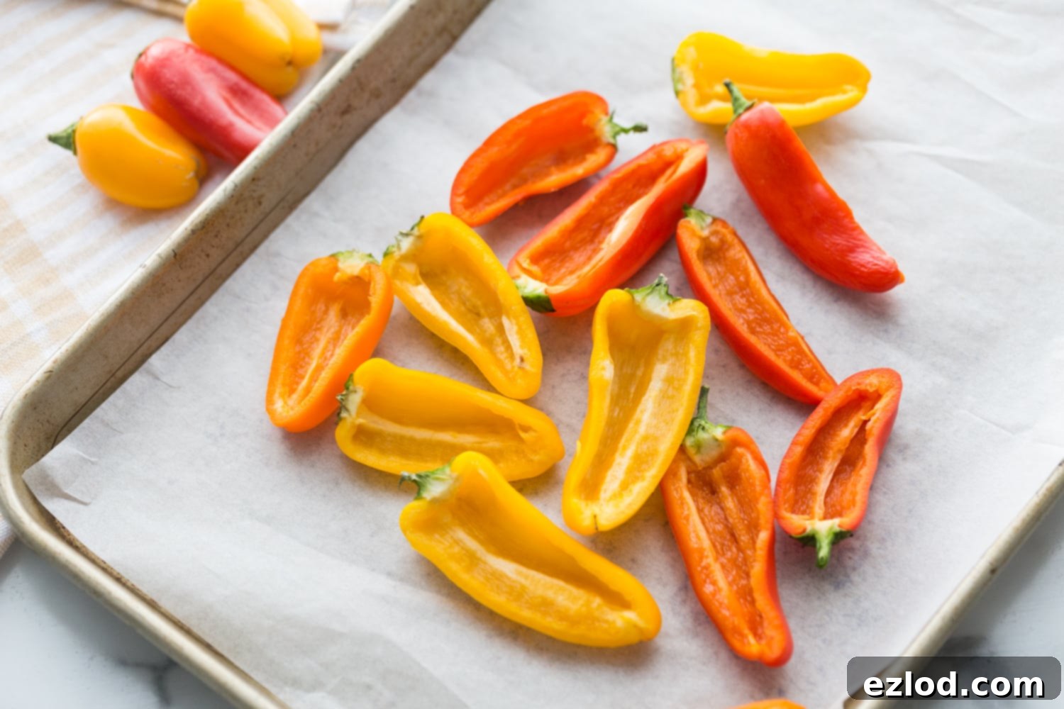 Fiery Buffalo Chicken Stuffed Peppers 8 Red, Orange, and Yellow halved, seeded mini bell peppers arranged neatly on a parchment-lined sheet pan, ready for filling.