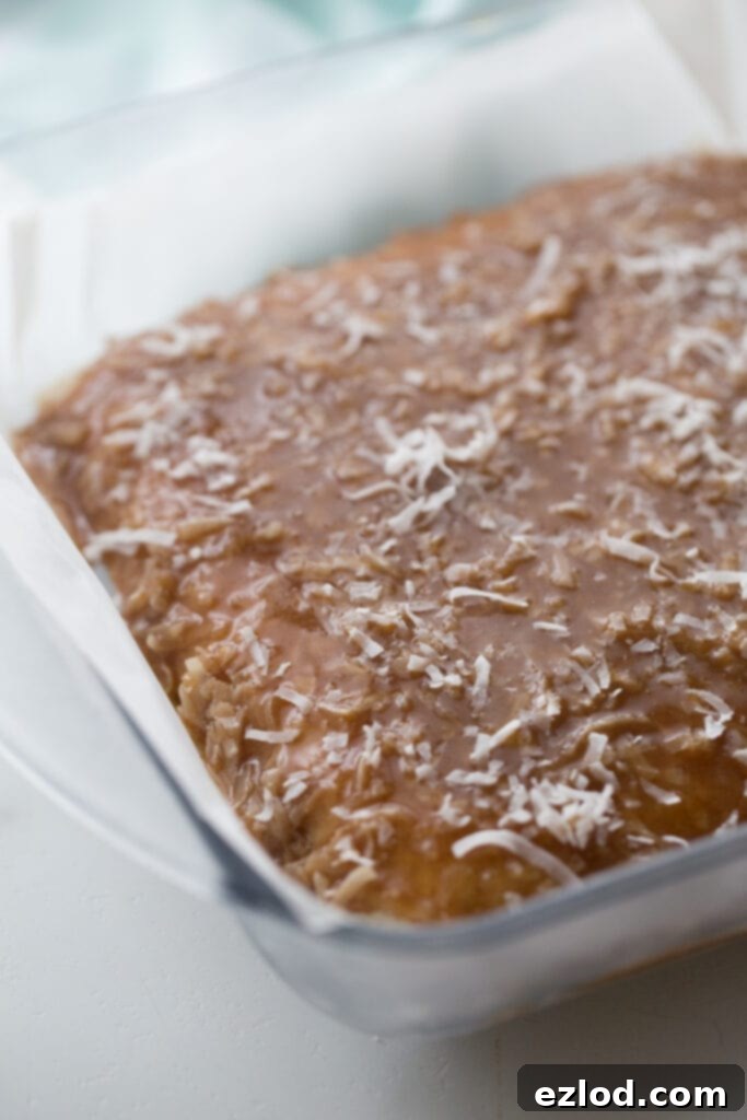 In-process photo of Healthy Samoas Cookie bars, with the rich homemade coconut caramel sauce smoothly spread as the top layer in a glass baking dish, ready for final chilling and cutting.