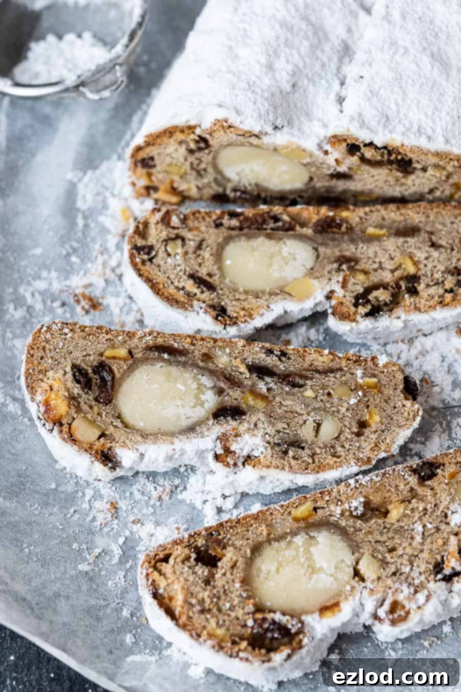 close up of slices of marzipan filled vegan stollen on a sheet of white baking parchment.