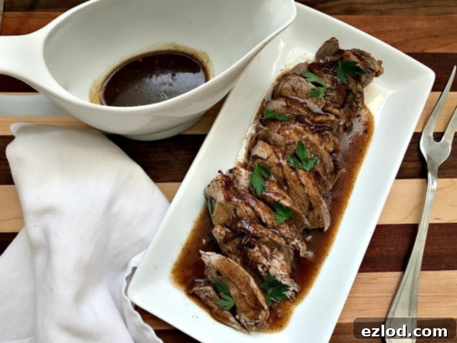 Instant Pot Balsamic Pork Tenderloin, sliced and drizzled with sauce, garnished with herbs.