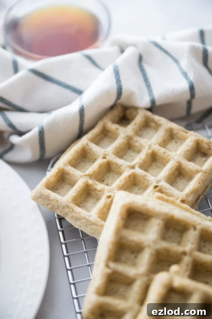 Stack of golden Gluten Free Make-Ahead Freezer Waffles topped with syrup, a convenient and healthy breakfast option.